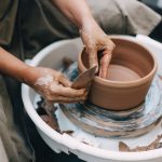 person making clay pot on white round plate