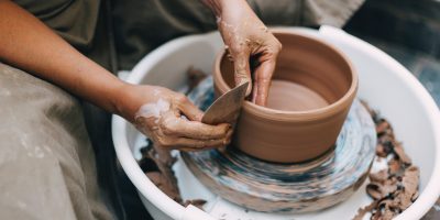 person making clay pot on white round plate